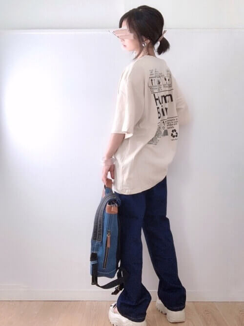 リュック×ベージュのロゴTシャツ×デニムパンツ×白のスニーカー