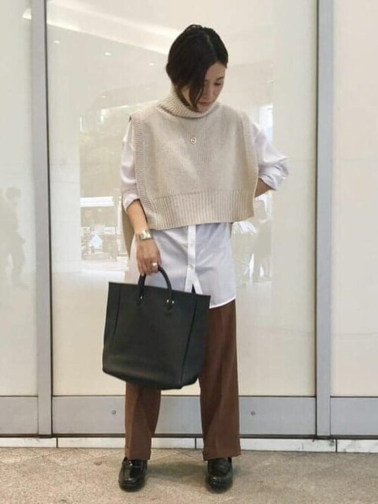 白シャツ×白のニットベスト×ブラウンのパンツ×黒のローファーの秋のオフィスコーデ