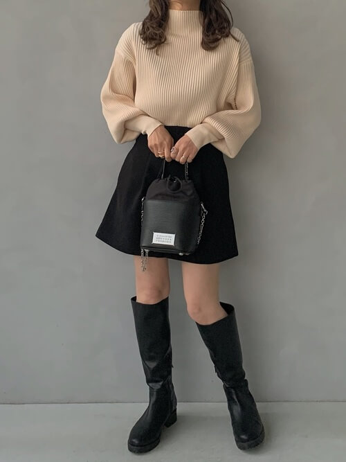 ロングブーツ×ベージュのハイネックニット×黒のミニスカート×黒のバッグ