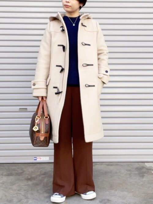 白のダッフルコート×ブルーのニット×ブラウンのスラックス×スニーカー×ブラウンのバッグ