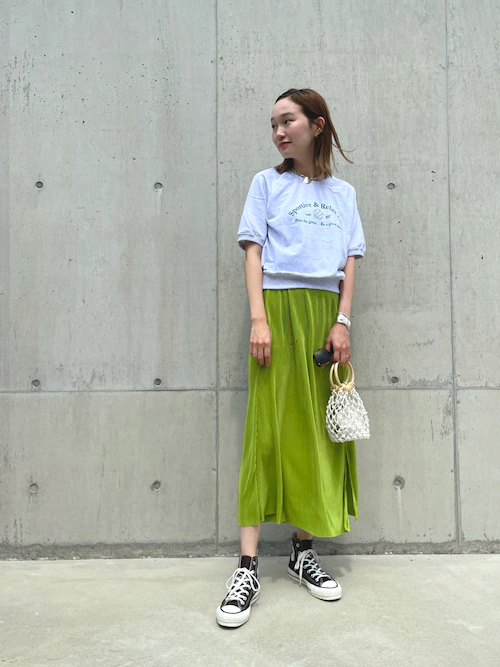 スウェットTシャツ×グリーンのスカート×黒のスニーカー×白のバッグ
